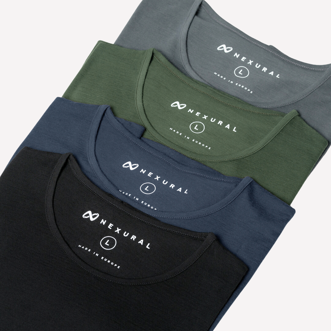 Ein Stapel aus vier gefalteten T-Shirts in Schwarz, Dunkelblau, Grün und Grau. Jedes Shirt trägt das Markenlogo „Nexural“ und das Etikett „Made in Europe“ in der Nähe des Kragens. Alle Shirts sind mit der Größe L gekennzeichnet.